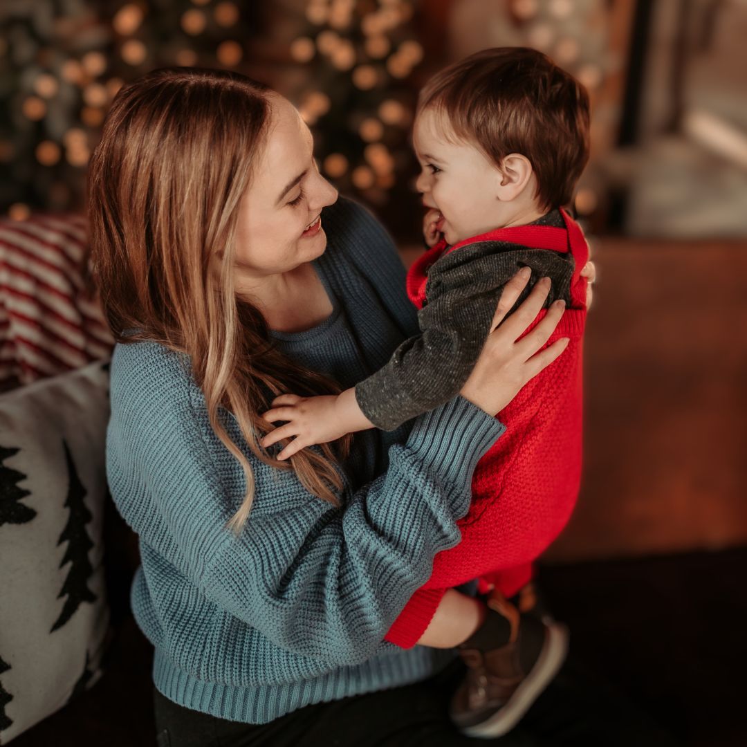 Mom Elizabeth holding her baby wearing red overalls for family and kids page