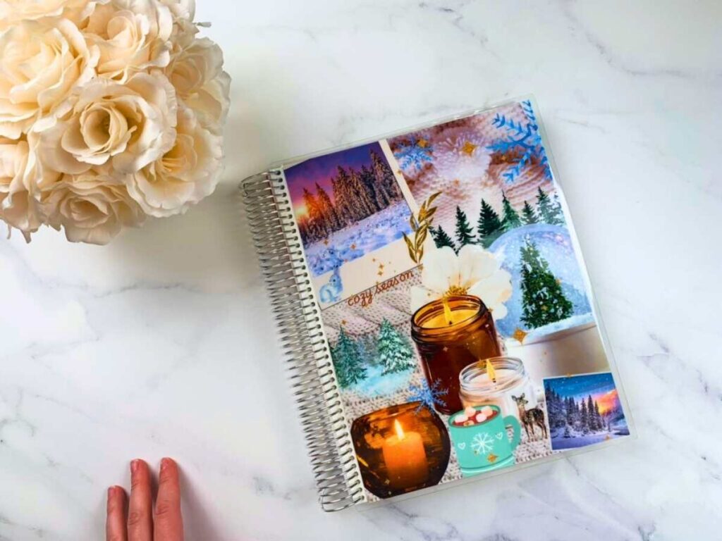 Teacher planner, hand, and white flowers on a white and gray marble counter