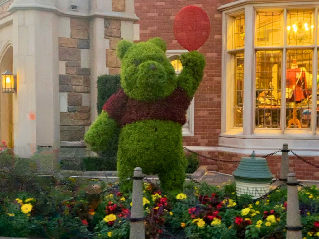 Winnie the Pooh topiary holds a red balloon in the UK section of EPCOT